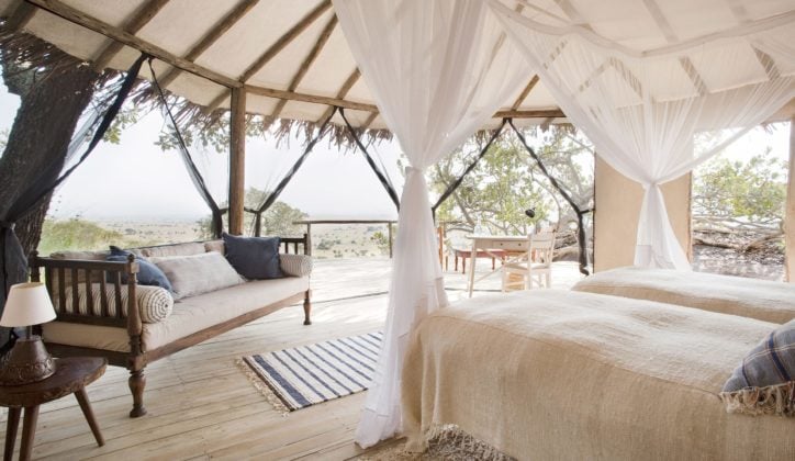 Interior of bedroom at Lamai Serengeti, twin beds with mosquito nets and sofa, open sides with view of the Serengeti National Park, Tanzania