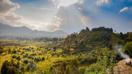 A view of lush greenery as the sun shines through parting clouds over Rwanda Volcanoes National Park